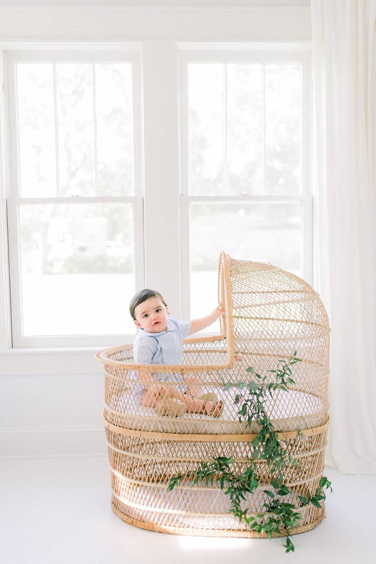 baby in wicker bassinet smiling at camera