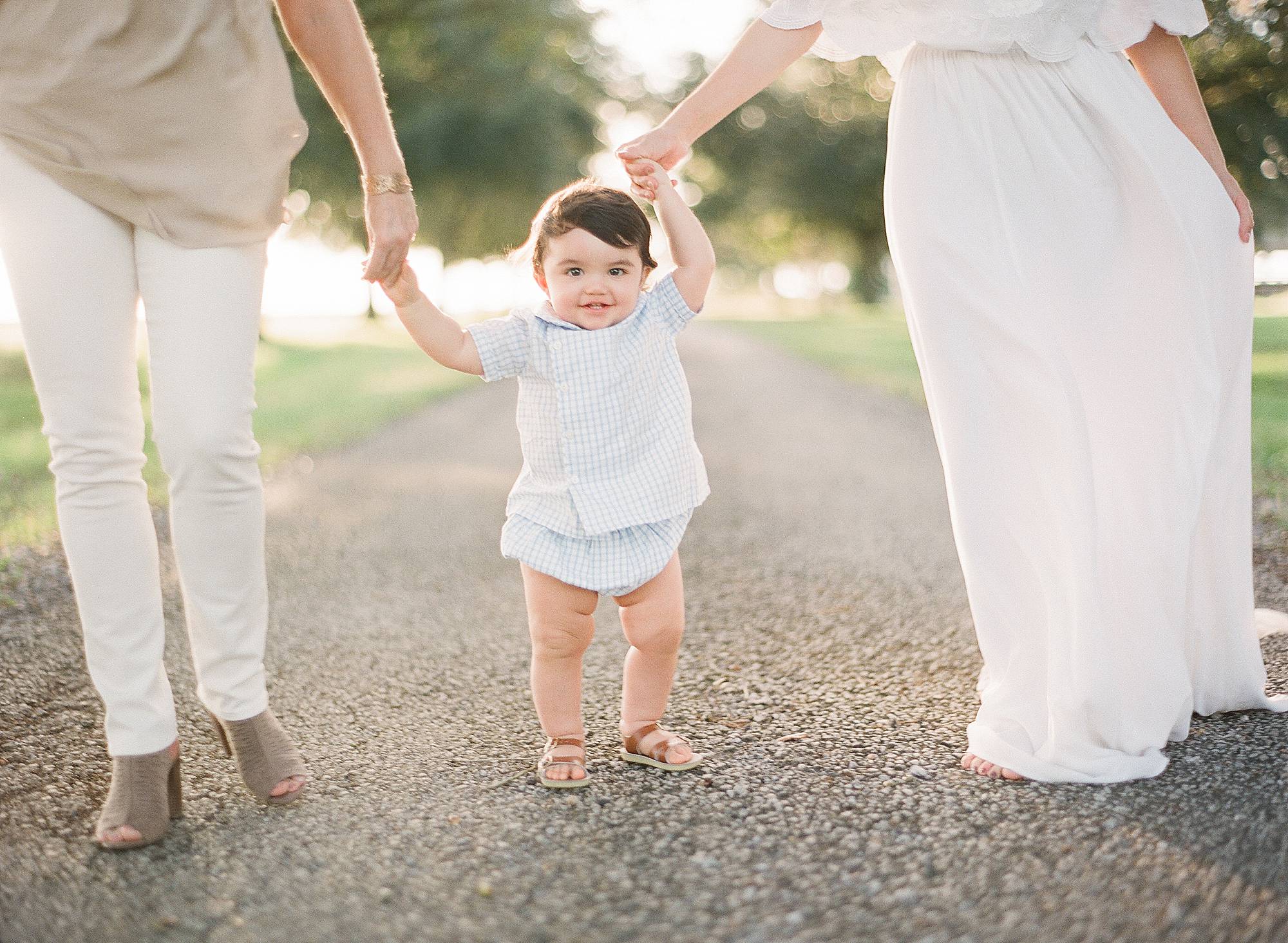 babies first steps holding parents hand