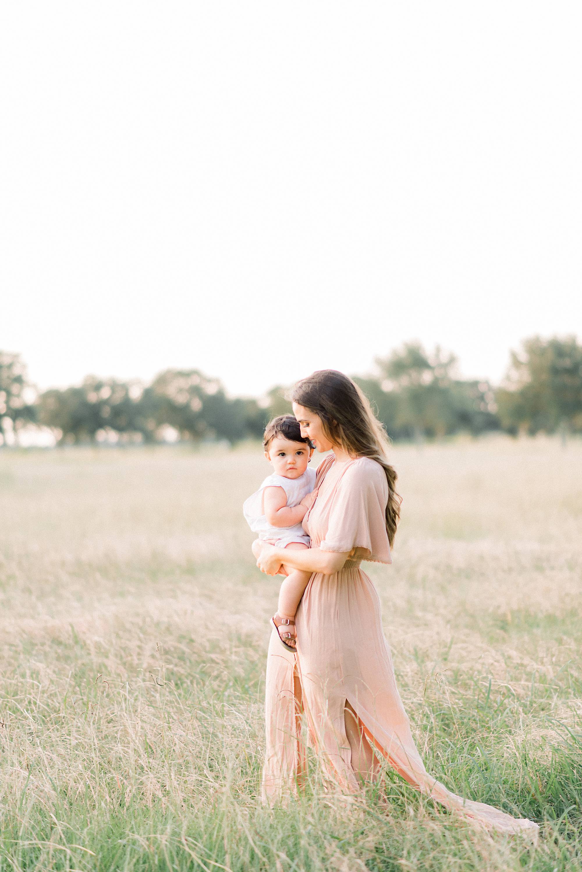 mother walking through the field holding her baby