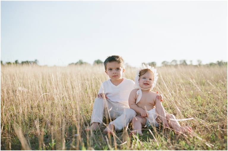 brother and sister in bonnet are photographed in field by natural light lafayette louisiana photographer
