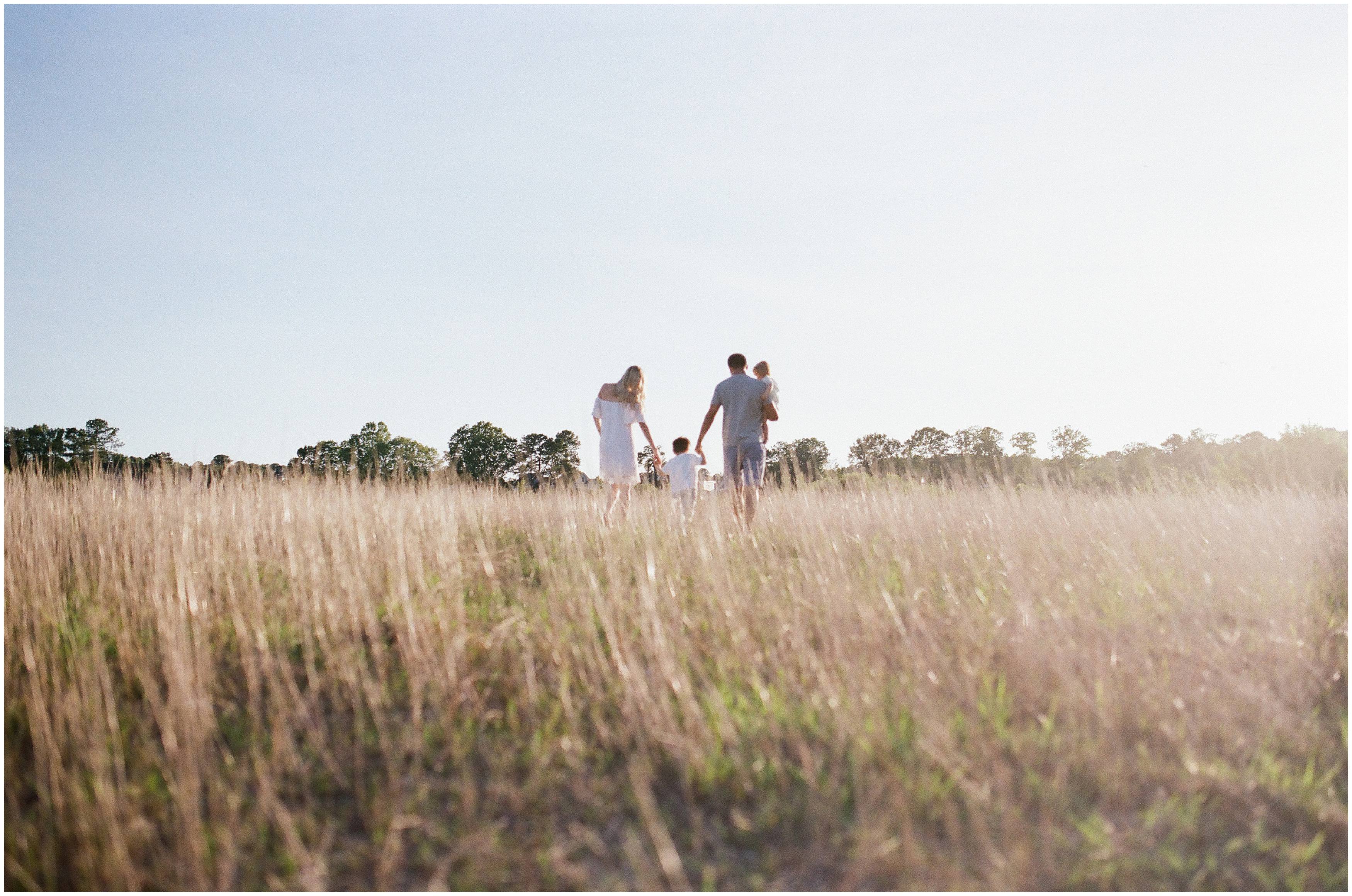 family walks hand in hand into the sunset photographed on film