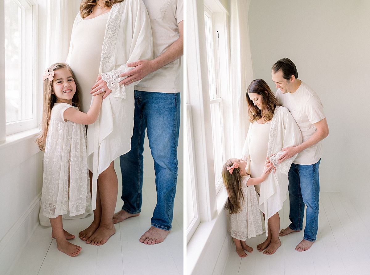 big sister hugs her moms pregnant belly in photography studio 