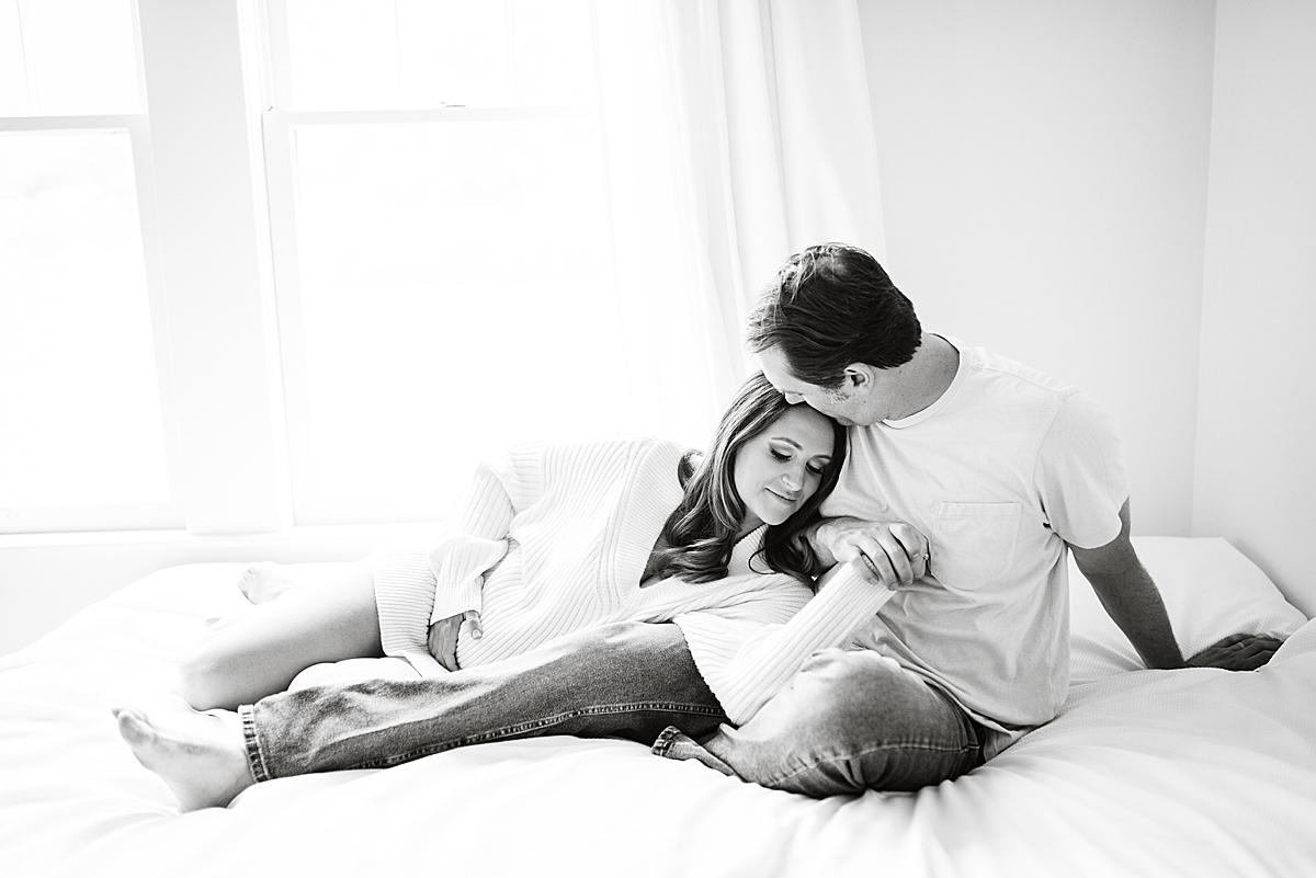 maternity photo parents in black and white film dad softly kisses moms head