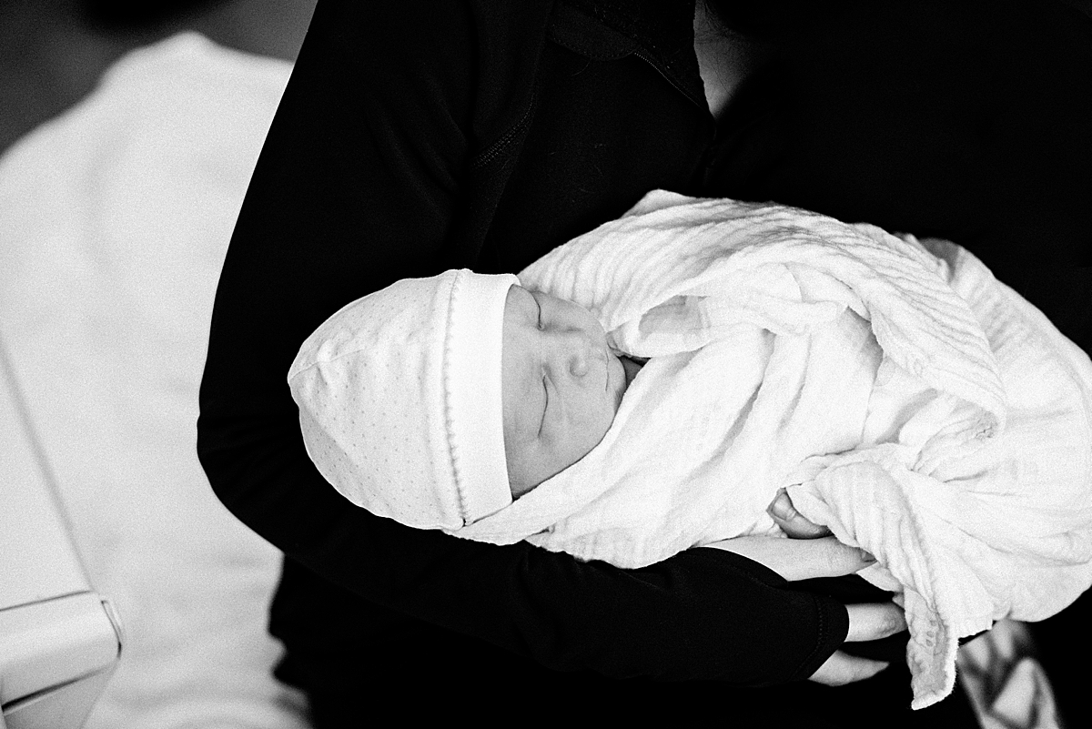 sleepy newborn baby in moms arms 