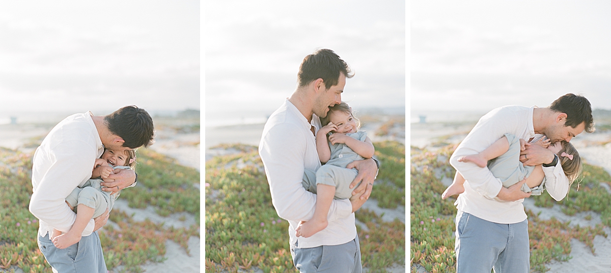 daddy holds his little baby girl as he tickles her and gives her kisses