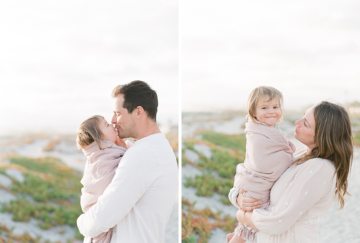 chilly day on the beach baby is wrapped in a blanket held by mom and dad