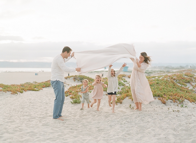 photography poses for family on the beach as kids run under blanket
