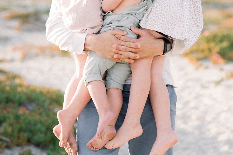 father holding all of his children detail photograph of his hands interlocked and childrens toes showing