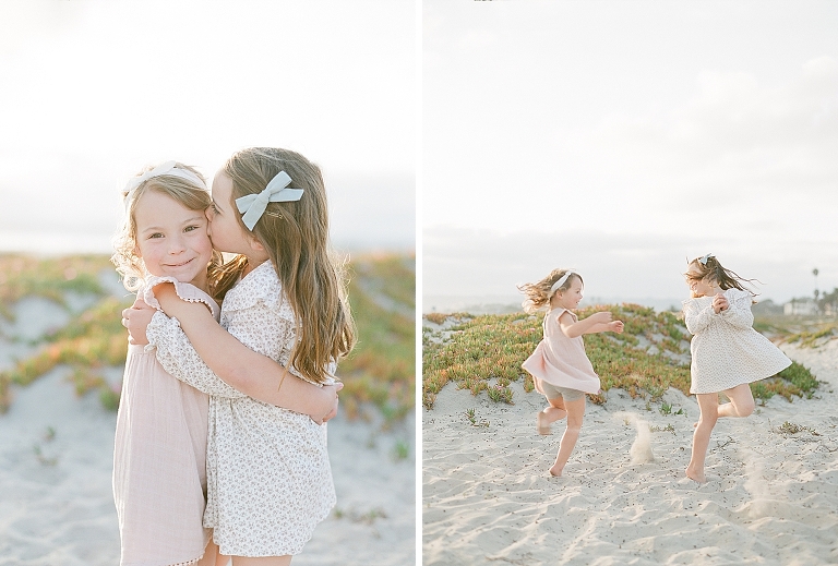 girls with bows twirling dresses in the sand on the beach while one sister kisses the other