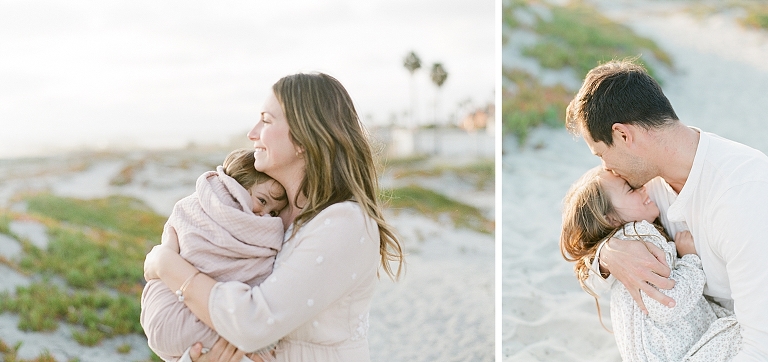 mom snuggles baby in a blanket while dad kisses older sisters forehead while on the beach of Huntington