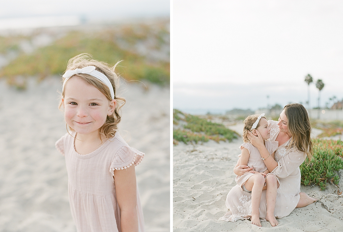 little girl sits on her moms lap as she brushes her hair 