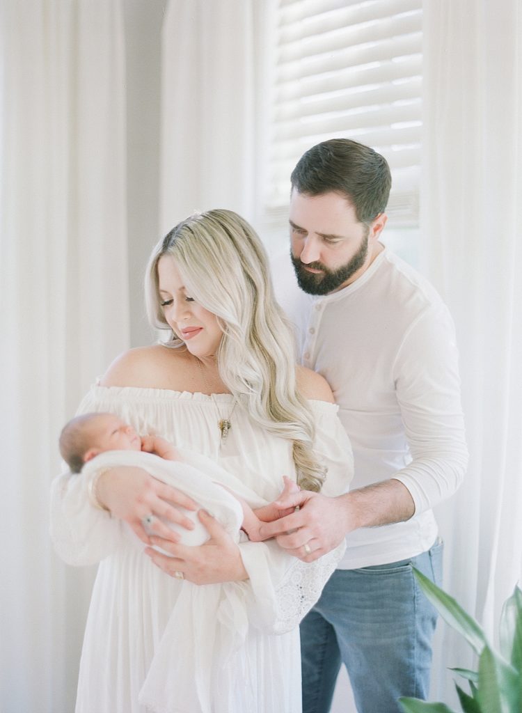 newborn baby boy held by parents at in home newborn session after years of infertility