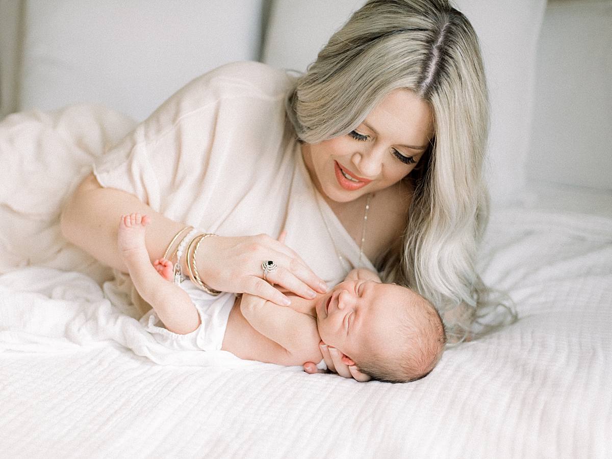 newborn baby has happy dreams as he lays with his mother while he sleeps 