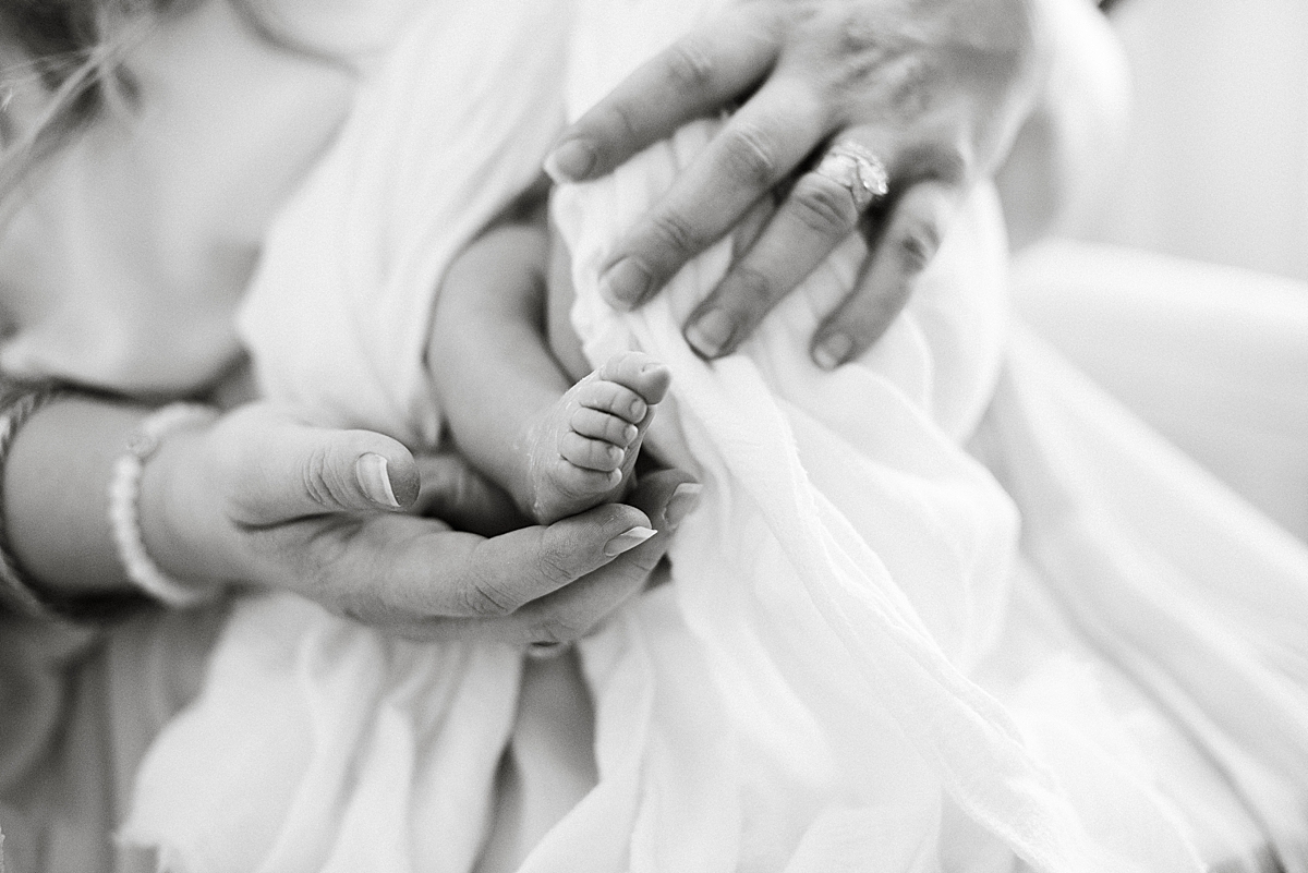 mother delicately holds newborn baby toes 