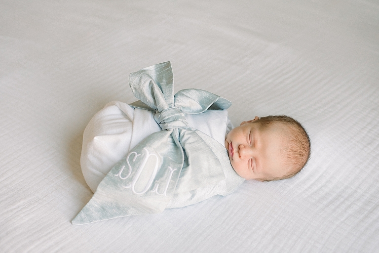 newborn baby boy swaddled in Beaufort Bonnet monogrammed blanket adorned with a bow