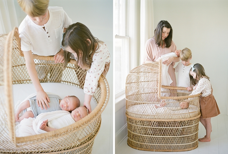 family stands together to admire newborn twins on their antique bassinet Siblings admire their new twin babies