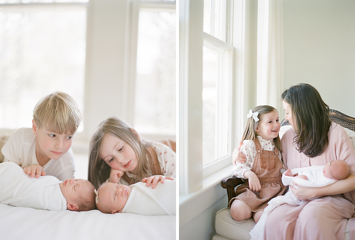 big sister laughs with her mom as she holds her newborn in her arms and makes her older child giggle