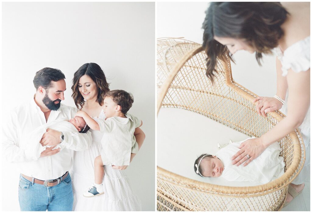 Newborn baby in basinet swaddled in a white wrap while she sleeps mom places her hand delicately on her 